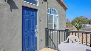 Un edificio con una puerta azul, una ventana y un balcón con una silla blanca.