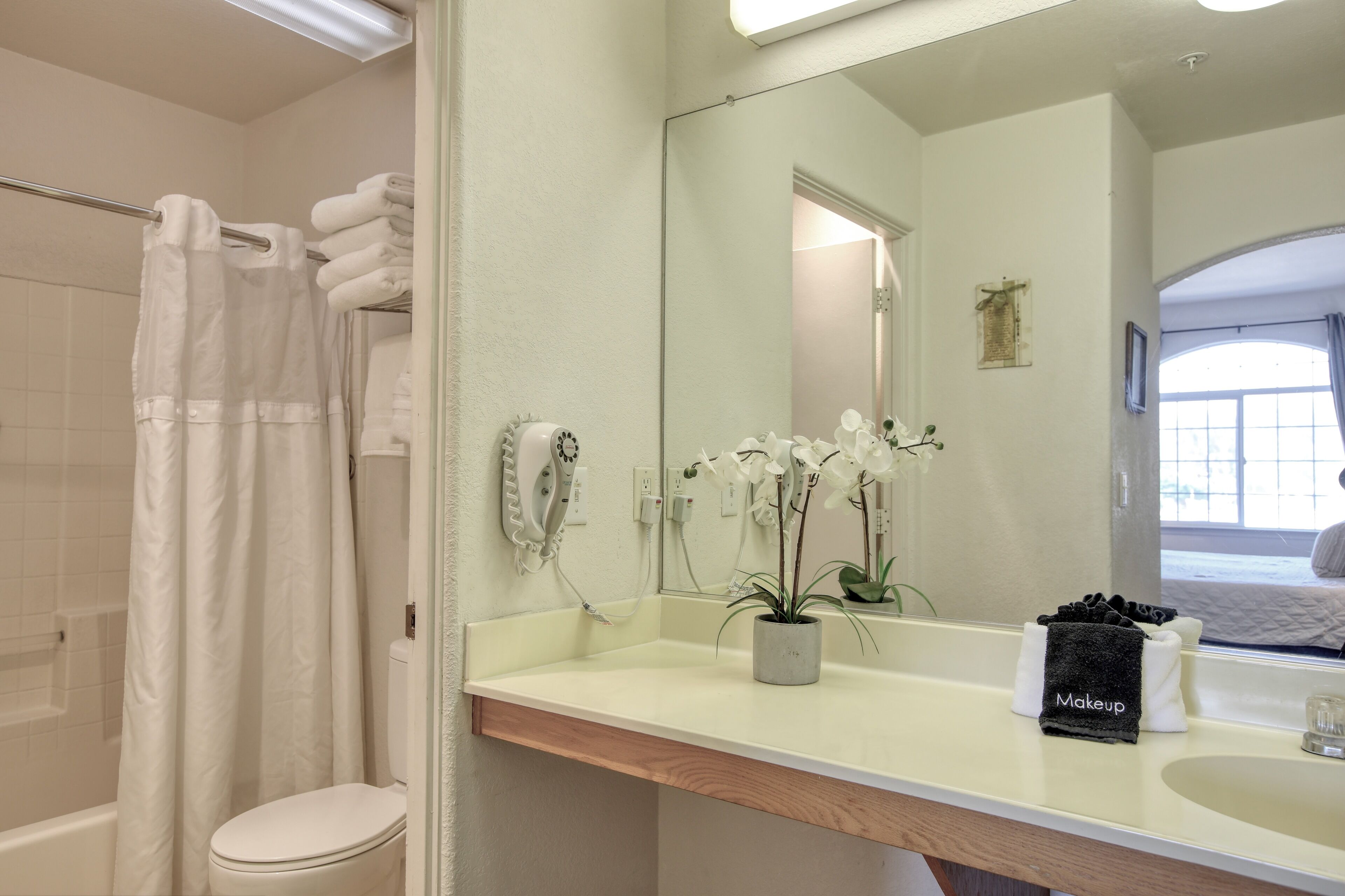 A bathroom with a shower, toilet, sink, and a mirror.
