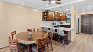 A modern kitchen with wooden cabinets, a central island, and a ceiling fan. - Stylish 2-Bedroom Beach Condo with Ocean-View Deck, Lush Pool Area & 2-Minute Walk to Flamingo Beach (Cabo Velas)