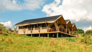 Een safarilodge met een plat dak en meerdere kamers, omgeven door een natuurlandschap.