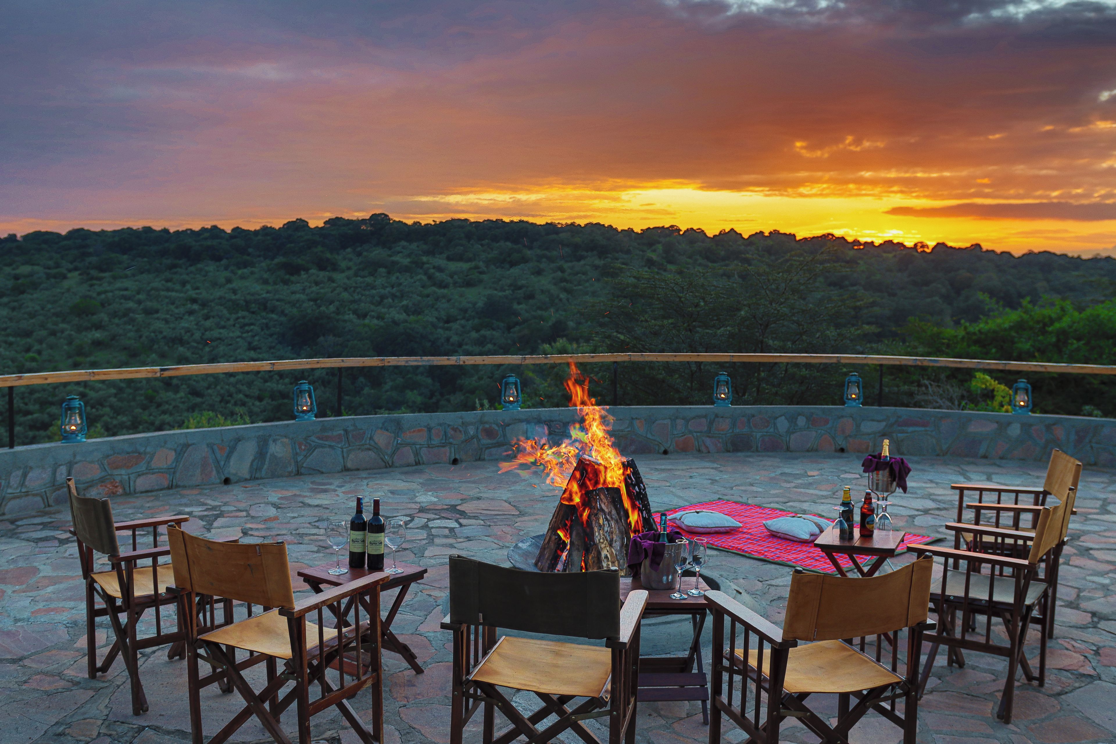 Un espacio de estar al aire libre con forma circular, chimenea, muros de piedra y faroles.