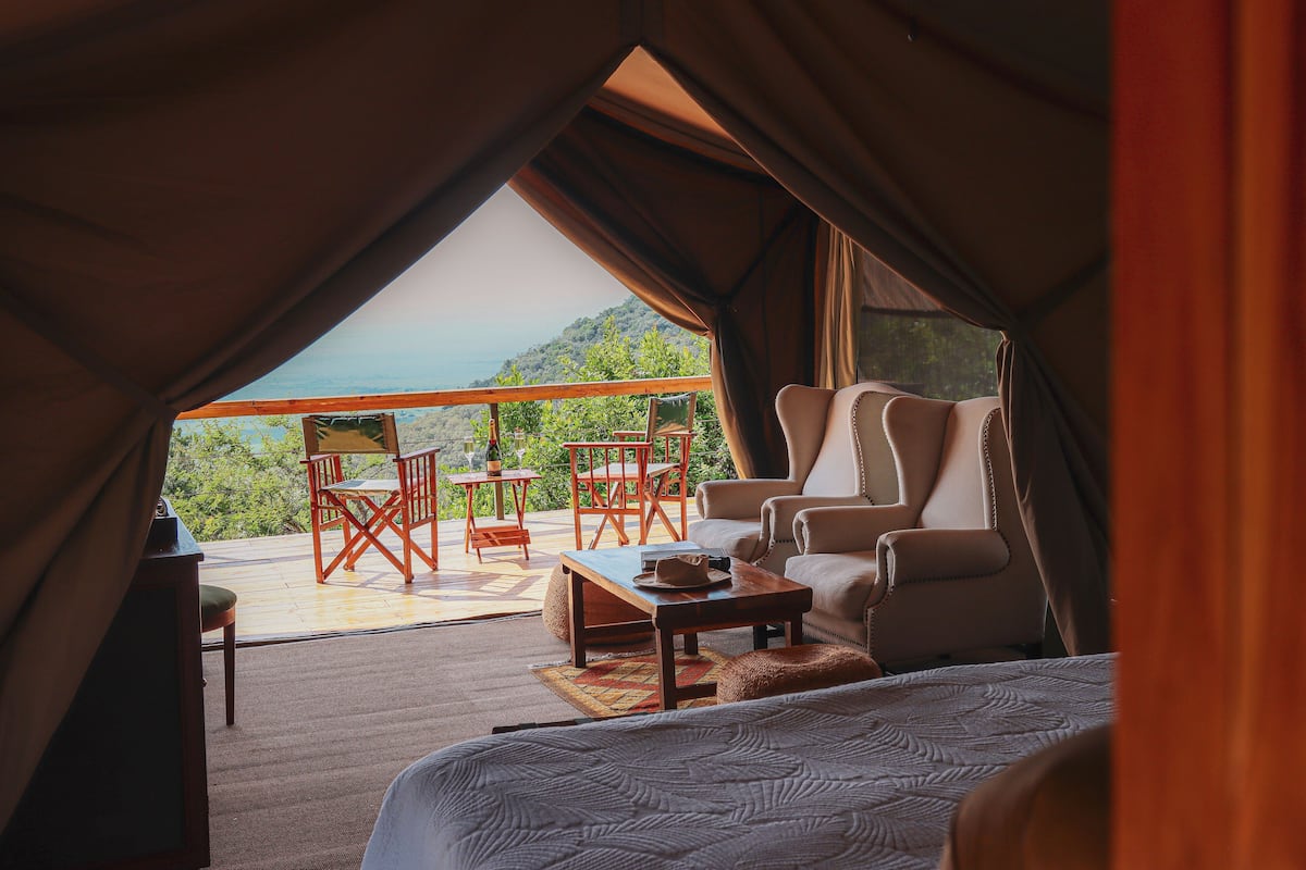 Een tentaccomodatie met een bed, een tafel en twee stoelen.