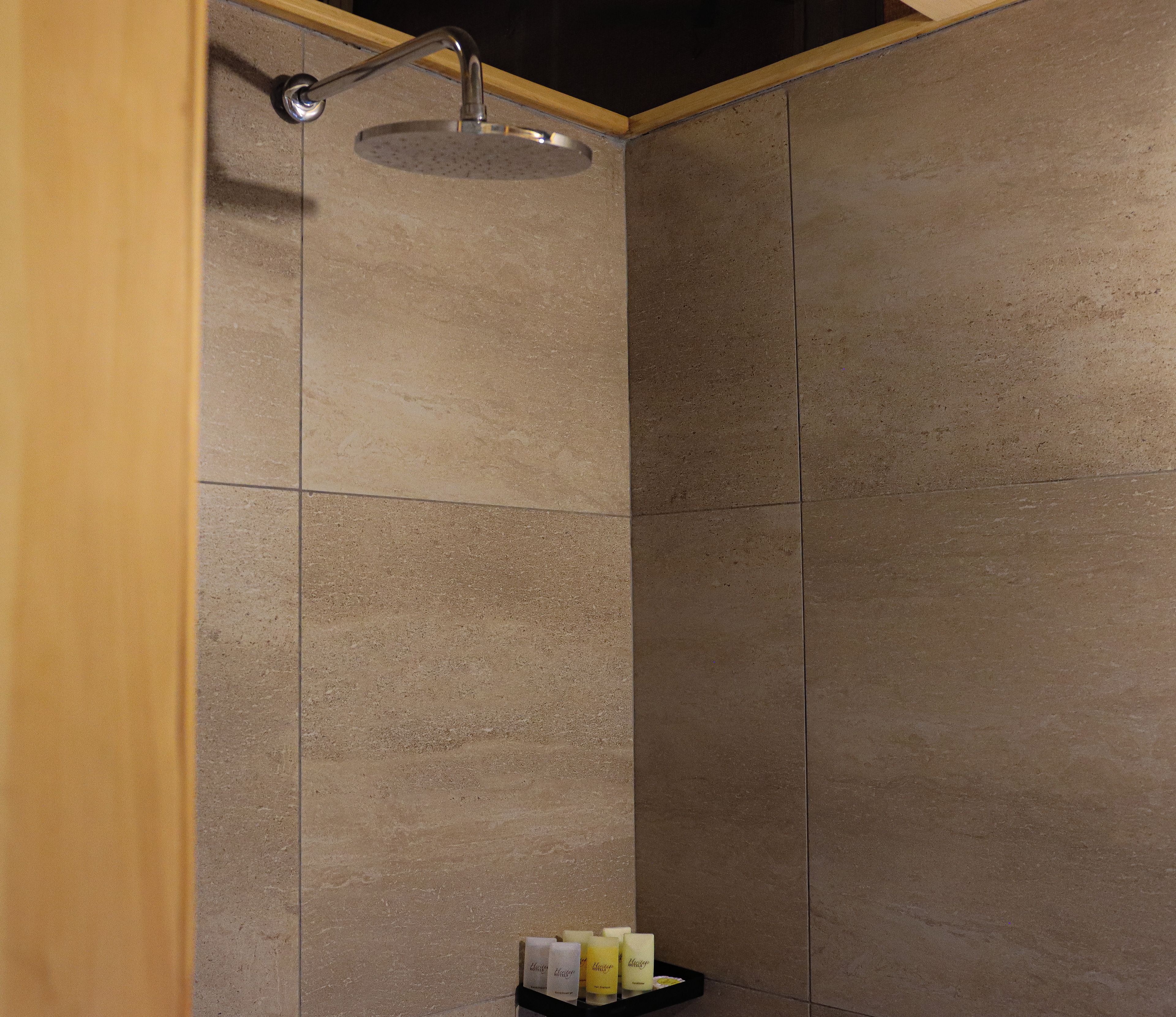 A shower with a handheld showerhead and a shelf with candles.