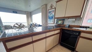 A kitchen with a tiled backsplash, wooden cabinets, a dishwasher, and a view of the balcony. - Beachfront Condo 3rd Floor Corner Unit sleeps 4, Spectacular Panoramic Ocean Vie (Seaside)