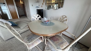 A dining area with a round table, four chairs, and a decorative mirror on the wall. - Beachfront Condo 3rd Floor Corner Unit sleeps 4, Spectacular Panoramic Ocean Vie (Seaside)