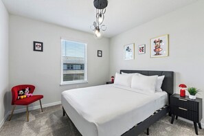 A bedroom with a bed, a nightstand, a chair, a window with blinds, and wall art.