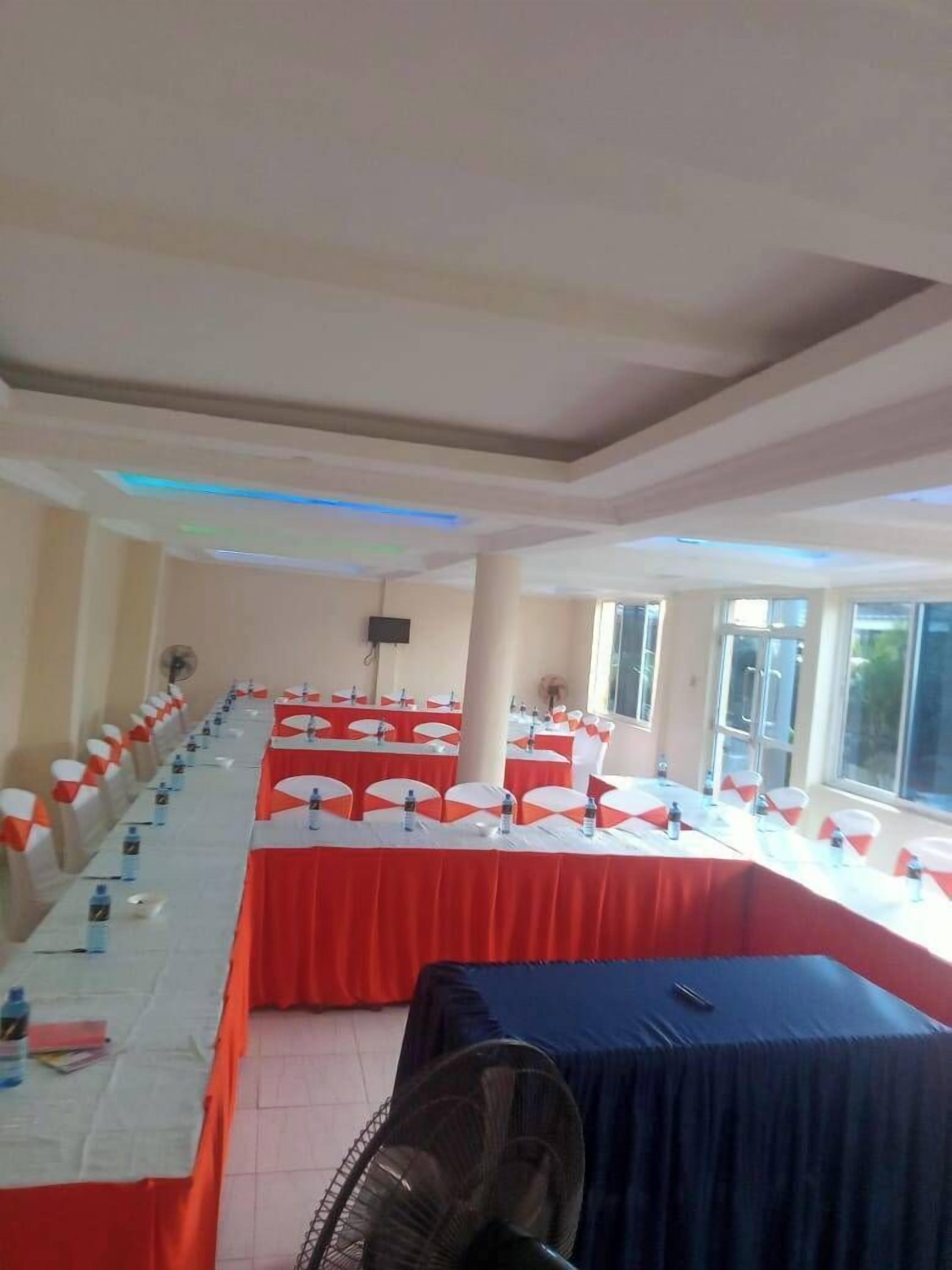 A conference room with long tables, chairs, and a fan.