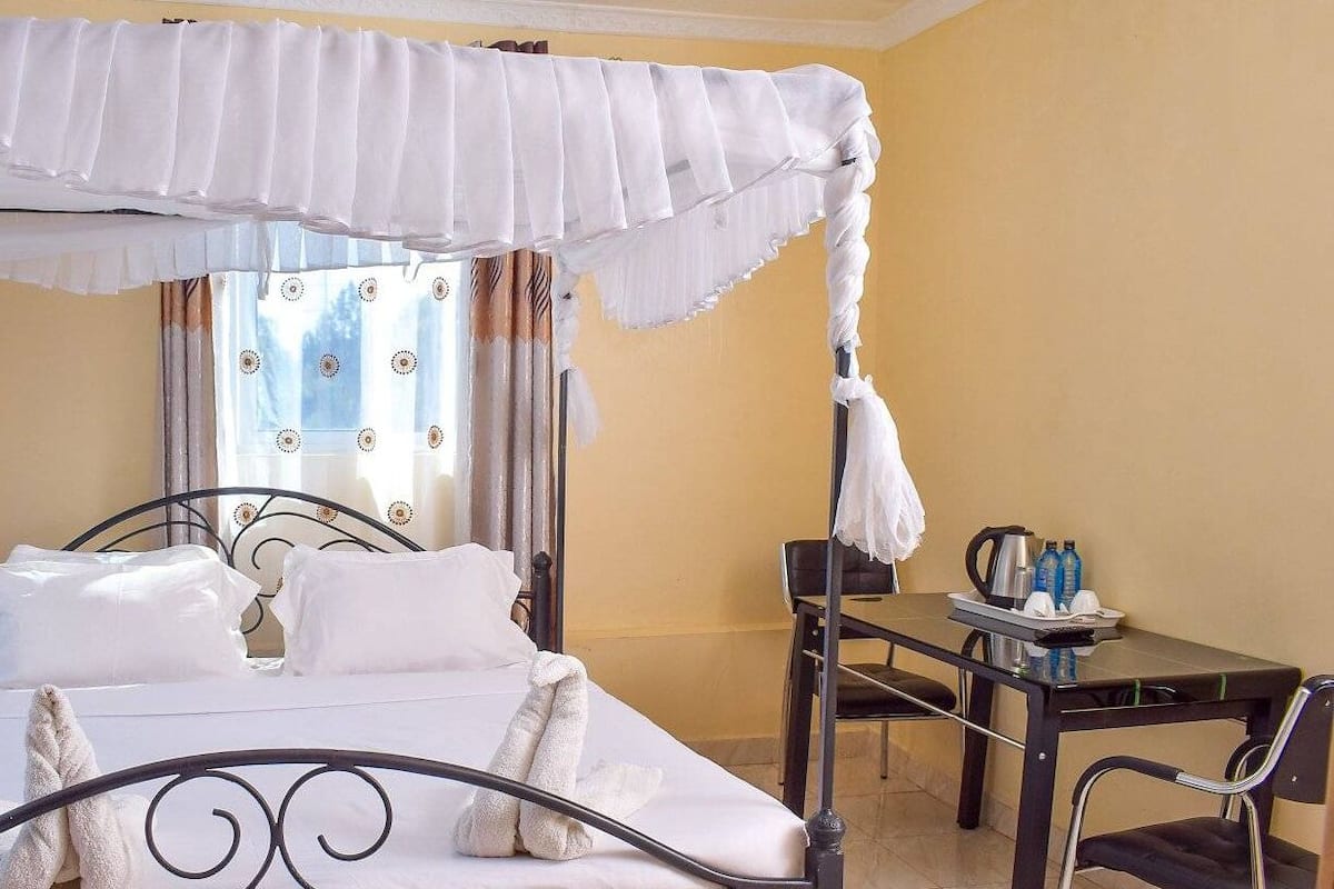 A hotel room with a bed, a table with chairs, and a window with curtains.