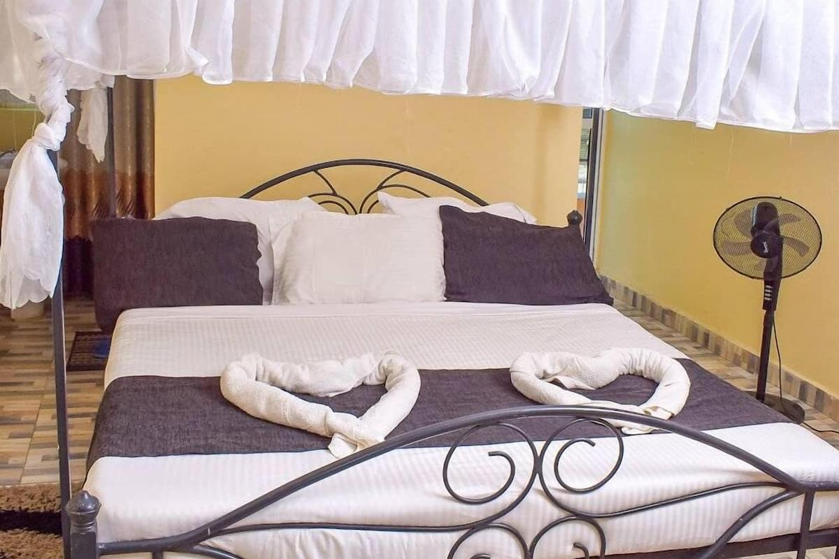 A bed with a canopy, pillows, and a fan.