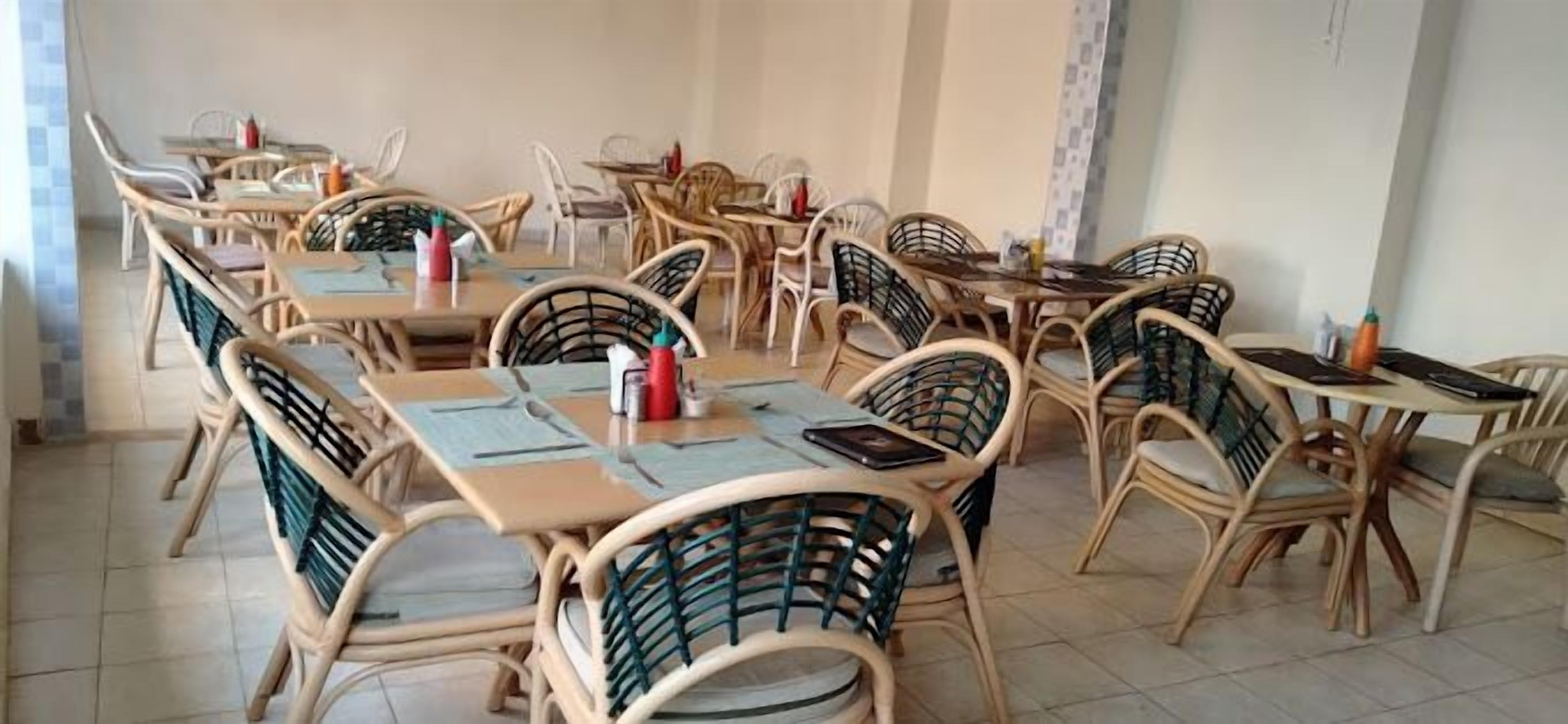 Un espace repas comprenant plusieurs tables et chaises, dont certaines sont accompagnées de menus et de condiments.
