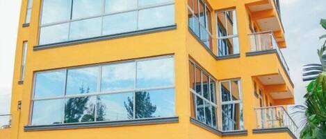 Un hotel de varios pisos con fachada amarilla, ventanas grandes y un letrero que dice 'Odelia Gardens Hotel'.