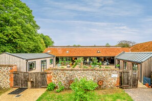 A rustic building with a stone wall, wooden gates, and a brick patio.