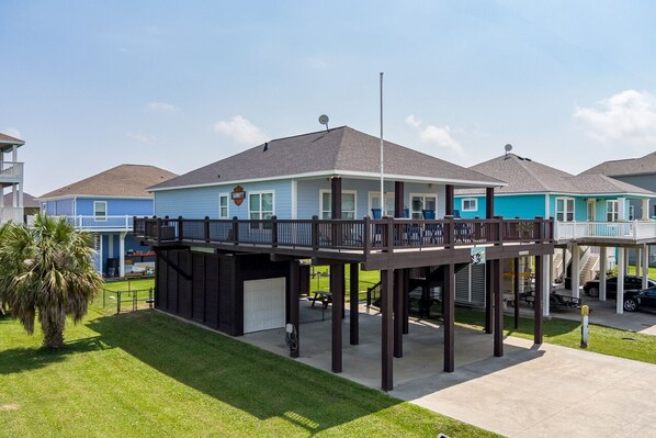 A residential building with a covered deck and a garage. - Outlaw's Inn - Gulf View, fenced yard, outdoor bar - 3 Bedroom (Crystal Beach)