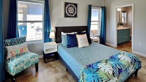 Ein Schlafzimmer mit Bett, Nachttischen, einem Sessel und Blick ins Freie.
