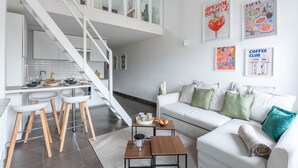 A modern living room with a white sofa, a coffee table, and a staircase leading to an upper level.