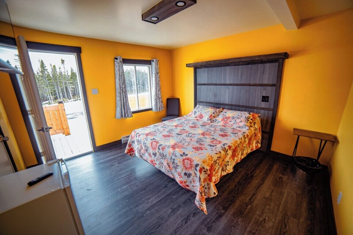 A bedroom with a bed, a window, and a door leading to a balcony.