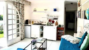 A compact living space with a kitchenette, a dining area, and a bedroom.