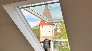 Huone, jossa on kattovalokuvio, portaikko ja näkymä tornille, jonka katto on punainen.