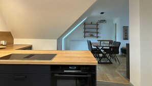 Moderni keittiö, jossa on puinen työtaso, integroidut kodinkoneet sekä ruokailutila pöydän ja tuolien kera.