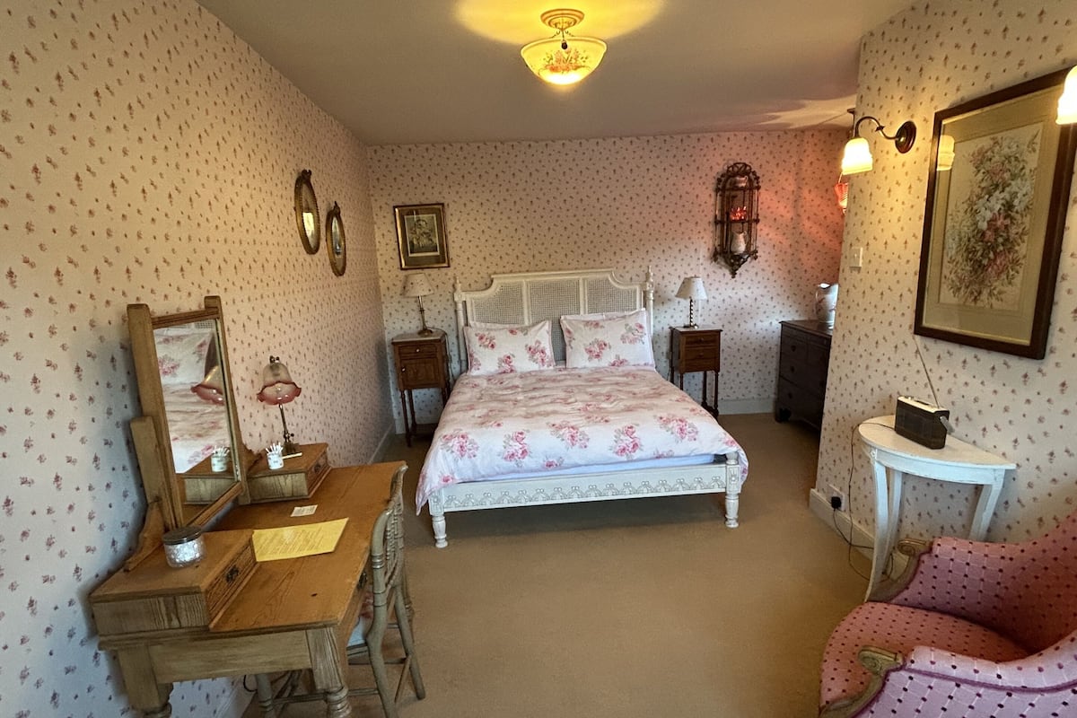A bedroom with a bed, a desk, a chair, and a dresser.