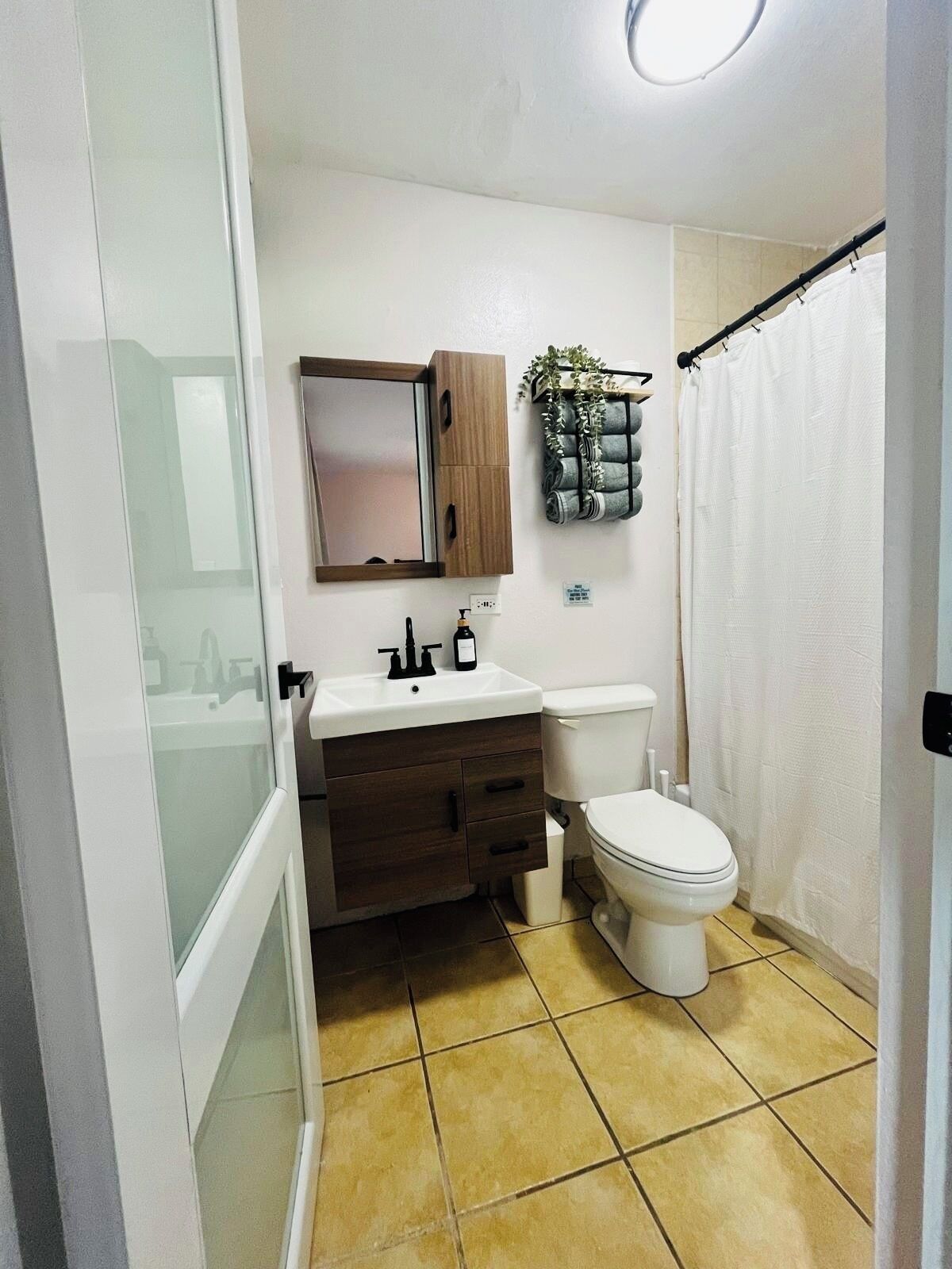 A bathroom with a white sink, dark wooden cabinet, and a toilet.