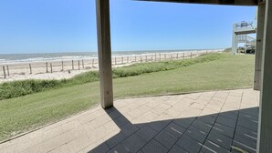 Et overdækket udendørs område med udsigt til stranden og havet.