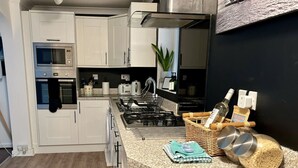 A modern kitchen with white cabinets, a built-in oven, a gas stove, and a granite countertop.