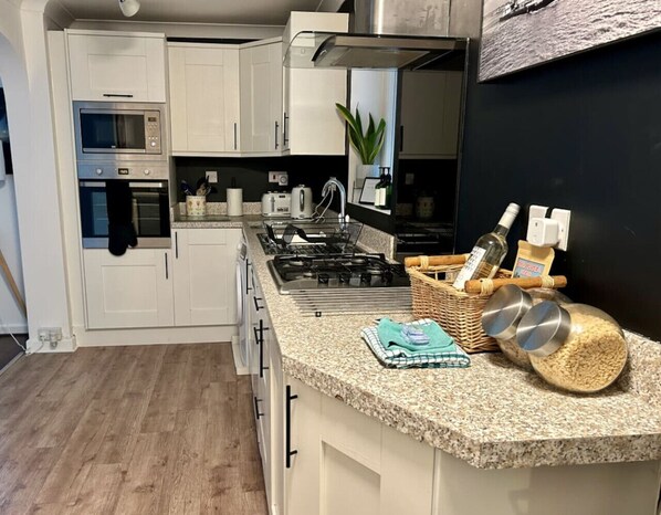 A modern kitchen with white cabinets, a built-in oven, a gas stove, and a granite countertop.