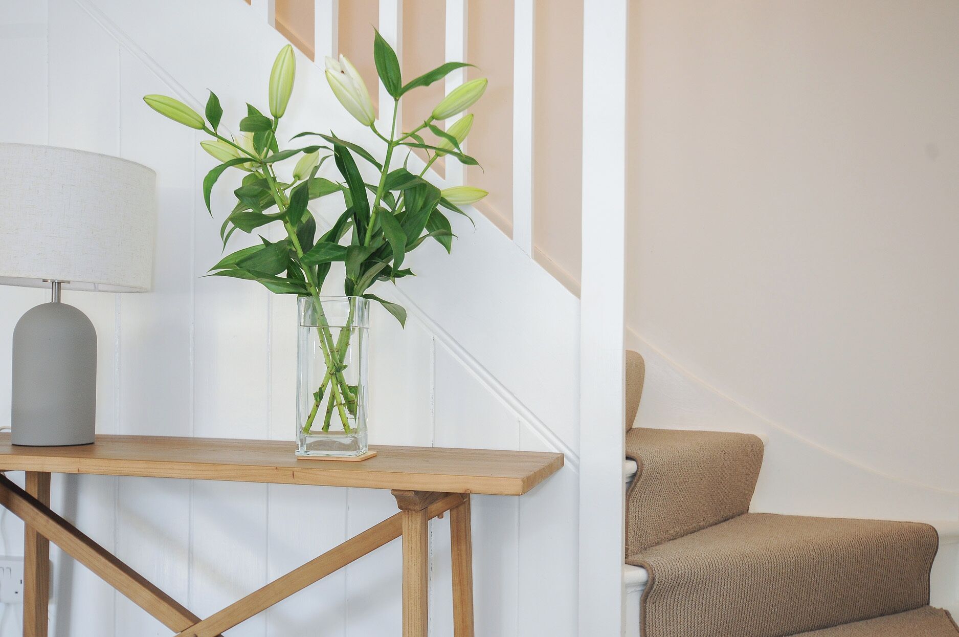 Una escalera con una planta en un florero de vidrio sobre una mesa de madera.