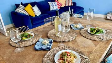Una mesa de comedor dispuesta con platos de comida, copas de vino y una botella.