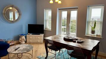 Una sala de estar moderna con una mesa de comedor de madera, paredes azules y un espejo grande.