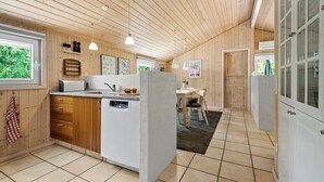 A modern kitchen with wooden paneling, a central island, and pendant lighting. - Stunning home in Oksbøl with sauna (Oksbøl)