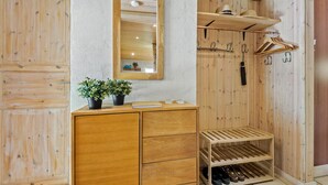 A wooden wardrobe with a mirror, a small shelf with plants, and a shoe rack. - Stunning home in Oksbøl with sauna (Oksbøl)