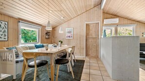 A cozy wooden interior with a dining area, a kitchen island, and a view of greenery outside. - Stunning home in Oksbøl with sauna (Oksbøl)