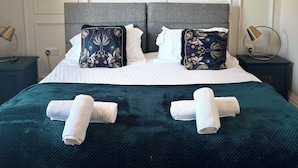 A neatly made bed with two pillows, a teal blanket, and two rolled towels. - No. 1 High Street - Boutique Rooms (Markinch)