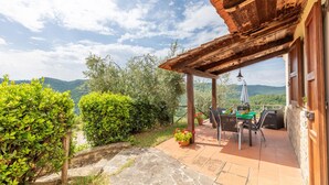 A covered outdoor seating area with a table and chairs, surrounded by greenery and a view of the countryside. - Gorgeous home in S. Maria in Tiberina (S. Maria in Tiberina)