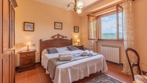 A bedroom with a wooden bed, two bedside lamps, a radiator, a window with a view, and a chair. - Gorgeous home in S. Maria in Tiberina (S. Maria in Tiberina)