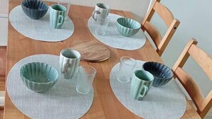 Ett matbord i trä med fyra stolar, dukat med genomskinligt glas och matchande skålar.