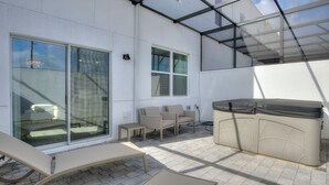 Un patio al aire libre con cerramiento de vidrio, un sofá, una mesa y un armario.
