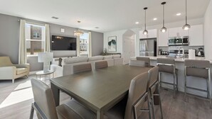 Amplia sala de estar con una gran mesa de comedor, un conjunto de sofás y una cocina equipada con electrodomésticos modernos.