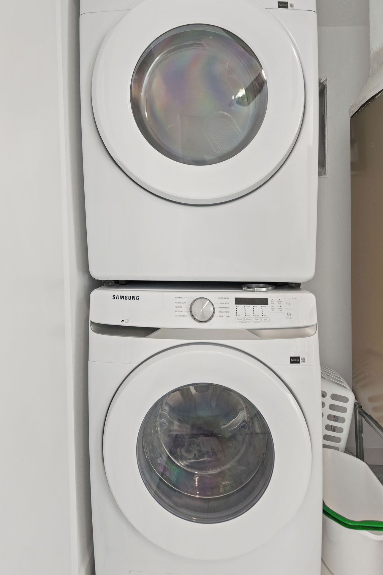 Two stacked front-loading washing machines in a laundry room.
