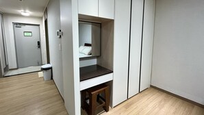 Habitació d'hotel amb armari integrat, una taula petita i un mirall.