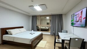 Habitació d'hotel amb llit, escriptori amb cadira, televisió i finestra amb cortines.