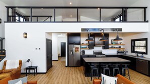 Una cocina moderna con una isla central, taburetes de bar y un comedor.