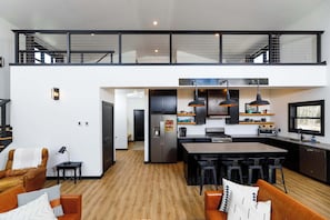 Una cocina moderna con una isla central, taburetes de bar y un comedor.