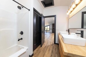 Ein modernes Badezimmer mit einer Badewanne, zwei Waschbecken und einem Holzwaschtisch.