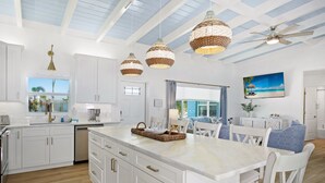 A modern kitchen with white cabinetry, a large island, and pendant lighting.