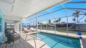 A pool area with a clear view of the water, lounge chairs, and a basketball hoop.