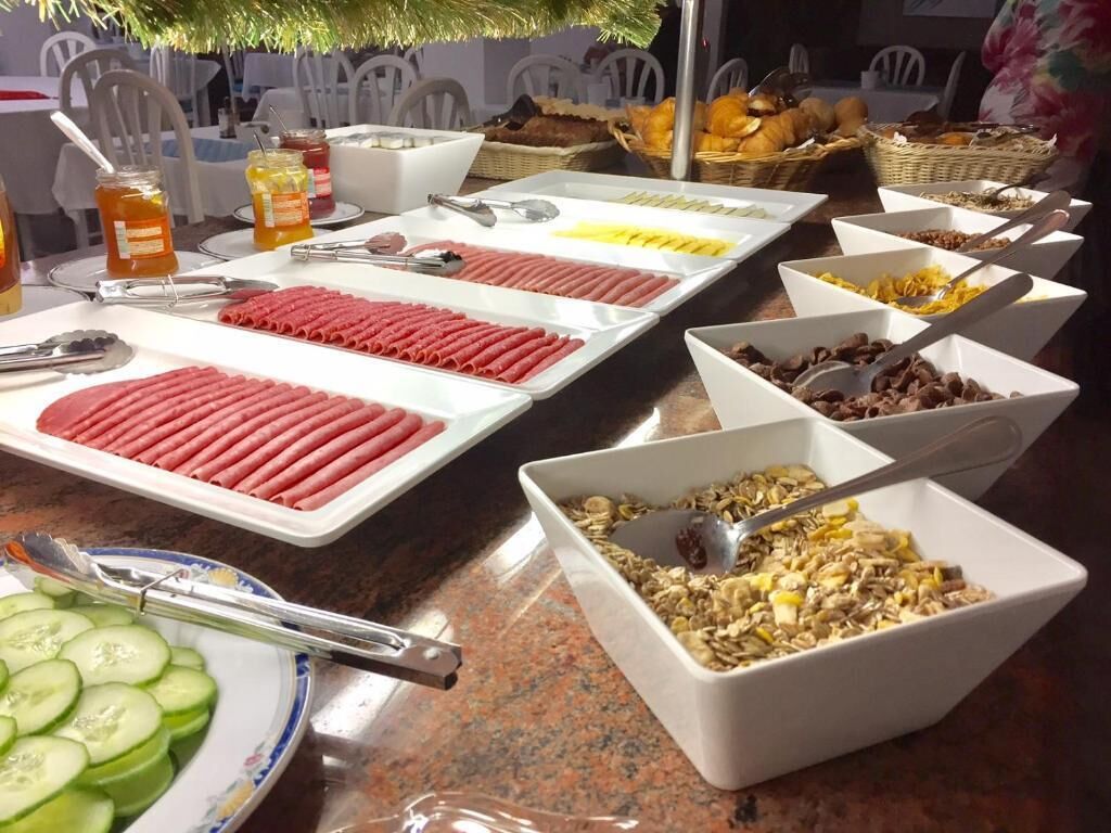 Une table de buffet proposant divers aliments, notamment des hot-dogs, des céréales et des fruits.