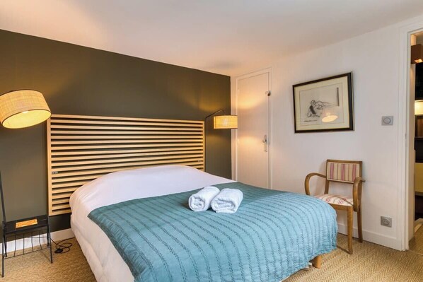 Une chambre d’hôtel avec un lit, une chaise, une lampe et un tableau encadré au mur.
